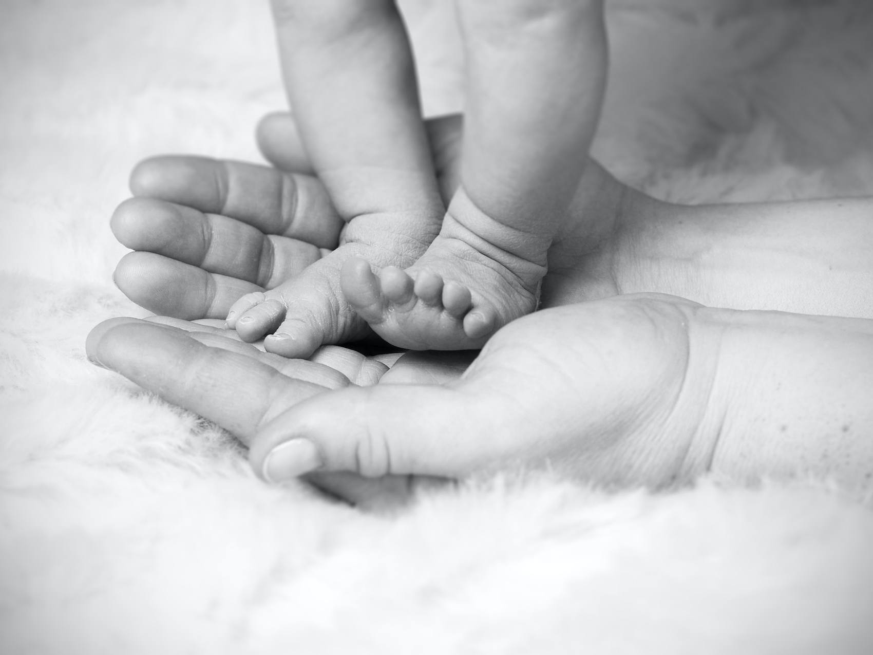 grayscale photo of baby's foot on human palm